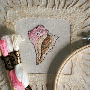 Embroidery of a colorful seashell, framed in Amate Paper.